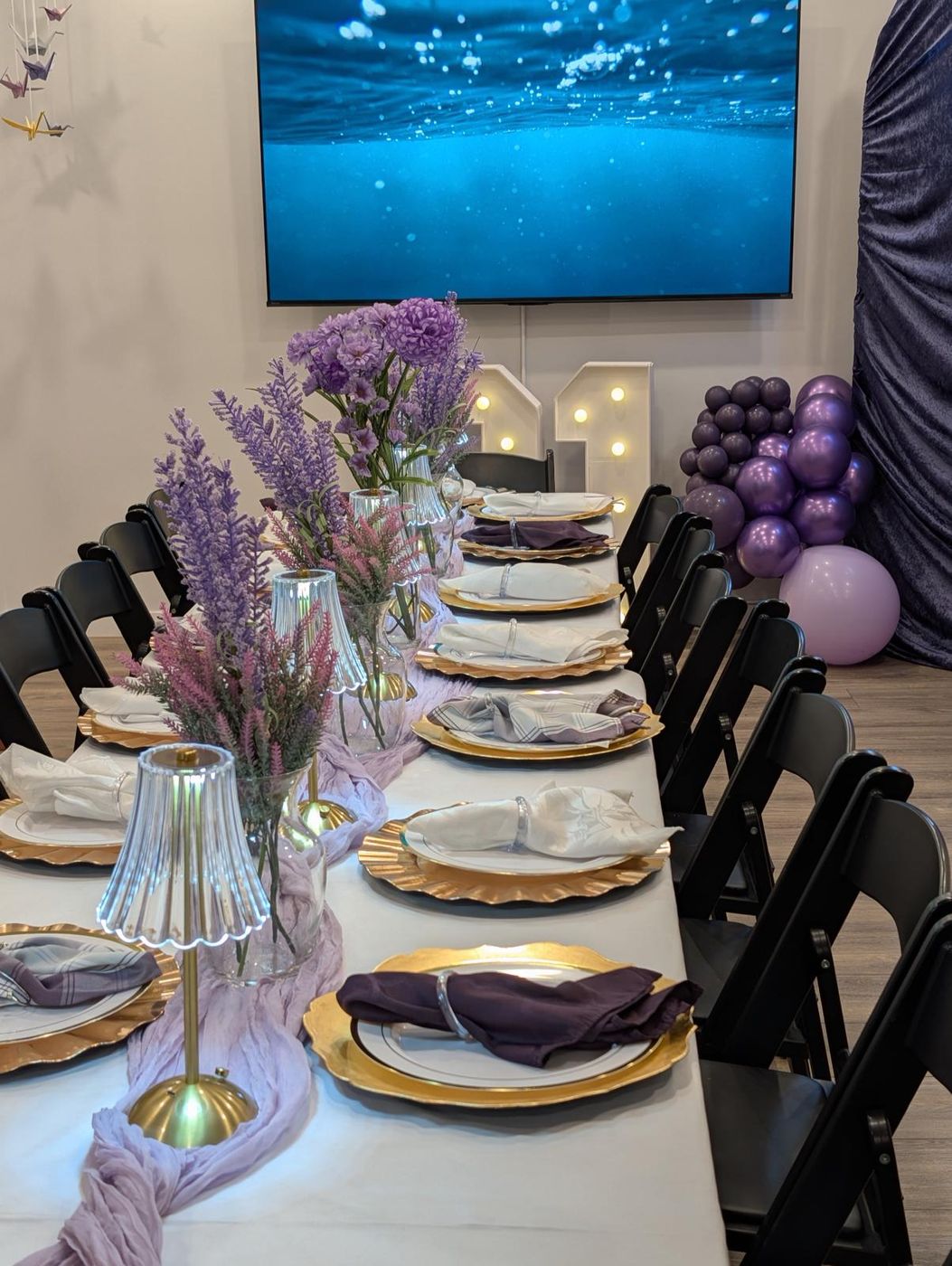 Lavender and chrome purple balloon garland on a velvet arch backdrop with a Happy Birthday neon sign